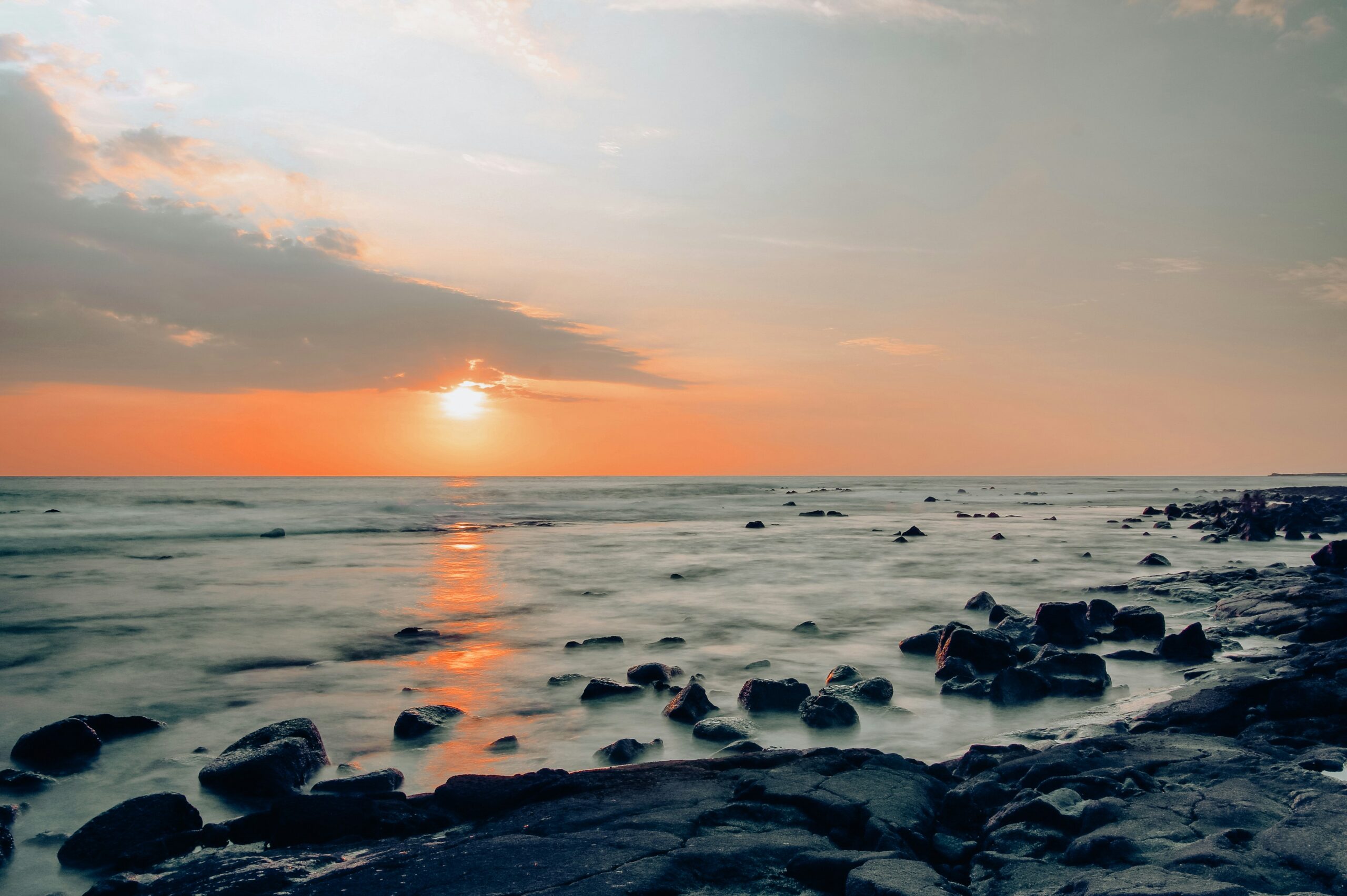 Sunset over the ocean from a lava rock shoreline in Kona