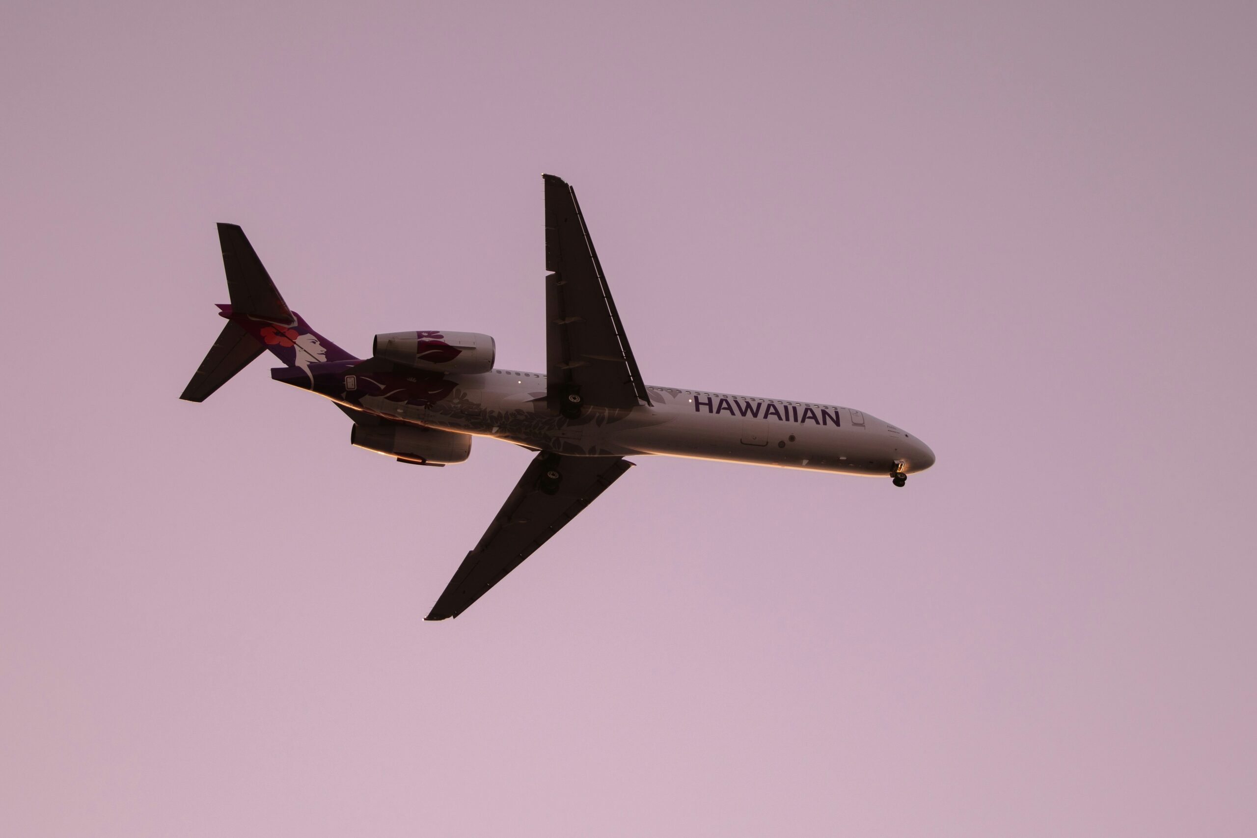 Hawaiian Airlines aircraft in flight against a pink evening sky